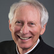 a man with white hair smiling at the camera